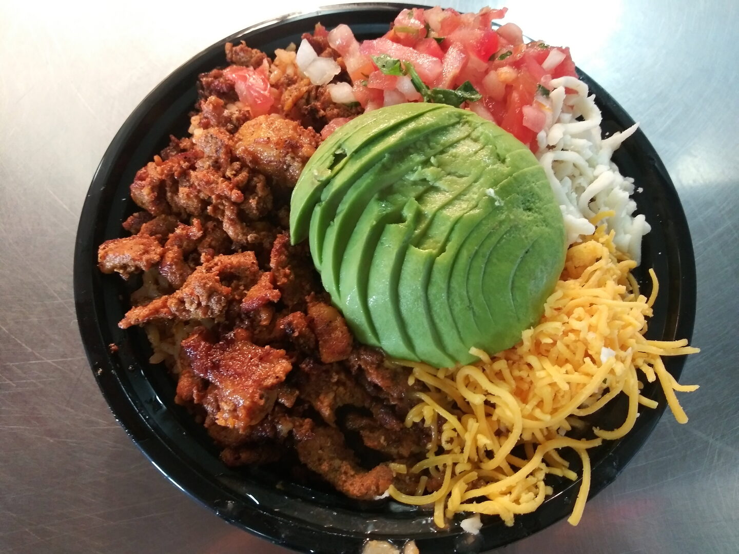 The Aldo's Bowl: meat, rice, pico, sliced avocado and cheddar in a black bowl